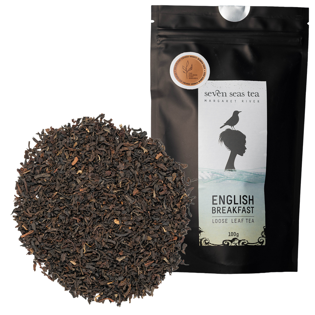 Organic English Breakfast loose leaf piled beside its black pouch with a medal sticker