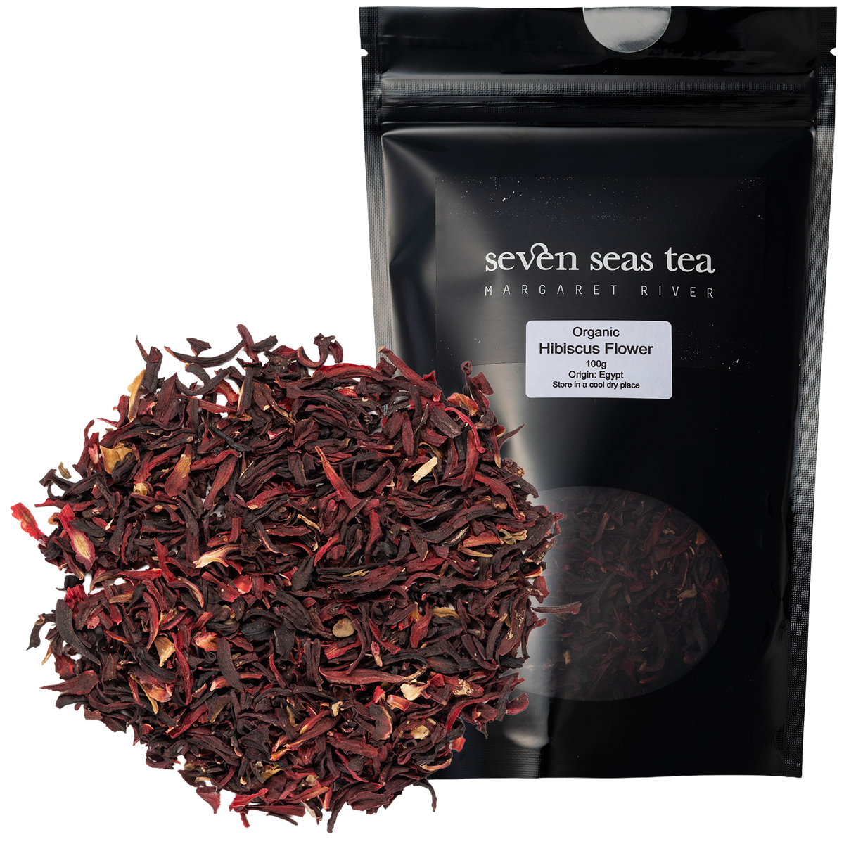 Loose leaf Organic Hibiscus Tea piled beside its black Seven Seas Tea pouch